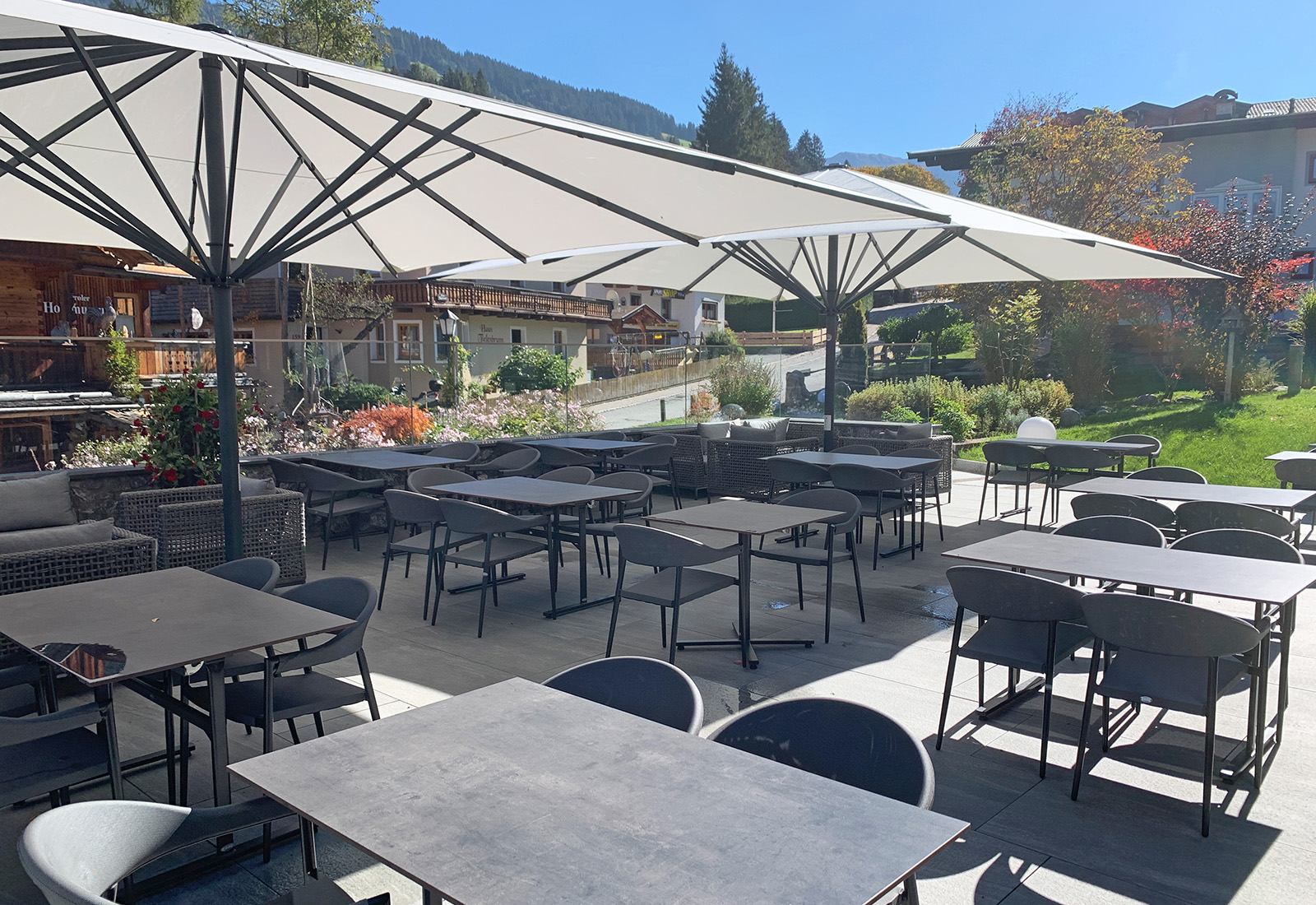 Hotelterrasse mit Sonnenschirmen, Sitzgruppen und Blick auf die umliegende Alpenlandschaft