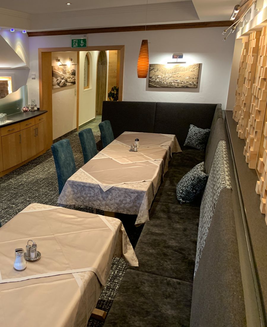 Restaurantbereich mit gedeckten Tischen, gepolsterter Sitzbank und Stühlen